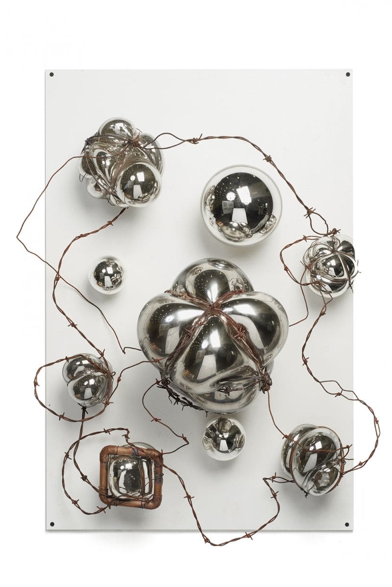 Metal sculpture made of bubble like clumps and spheres connected by barbed wire.