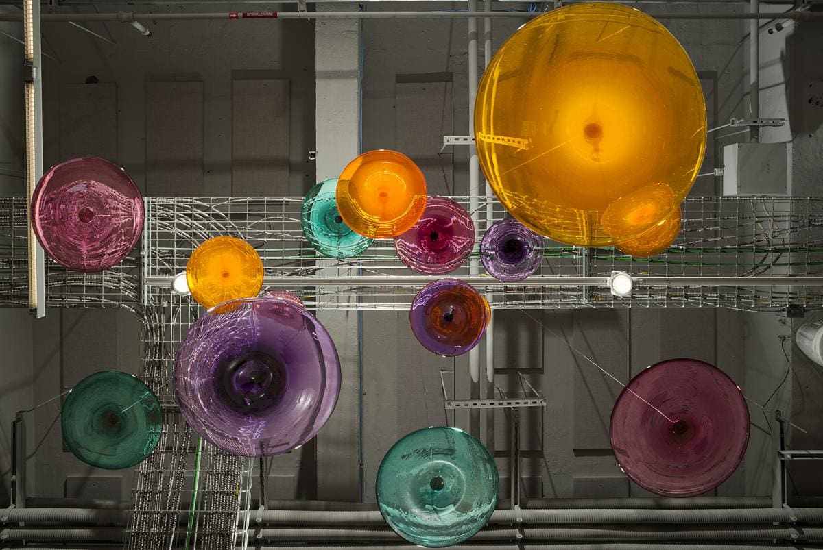 A display case full of spherical yellow, purple, blue and pink glass sculptures.