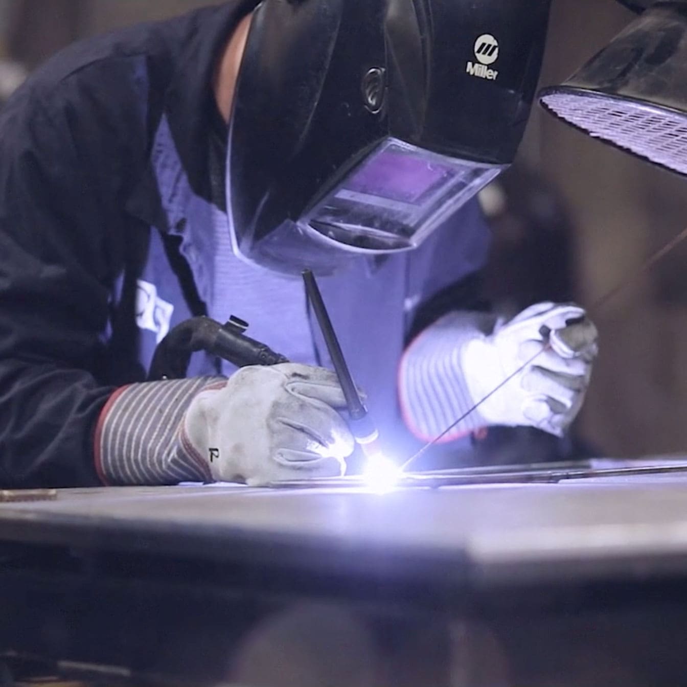 Close up photo of a masked welder working on a metal art piece.