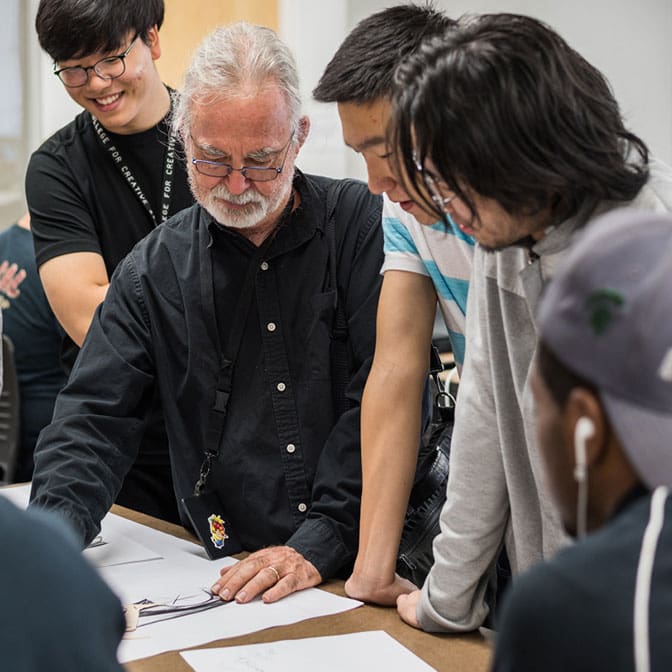 Photo of a professor instructing students at a work table.