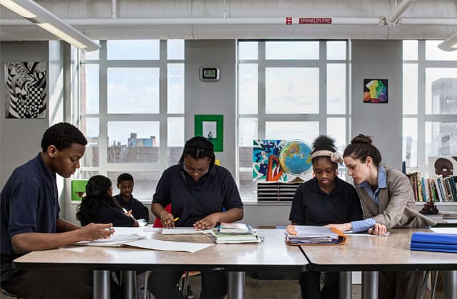Students gathered around a table drawing in a classroom