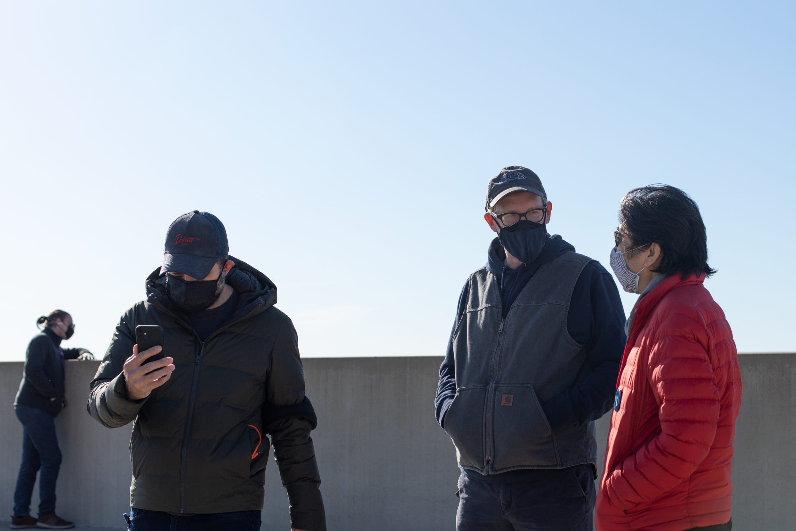 Don tuski standing with colleagues on a rooftop, all wearing masks