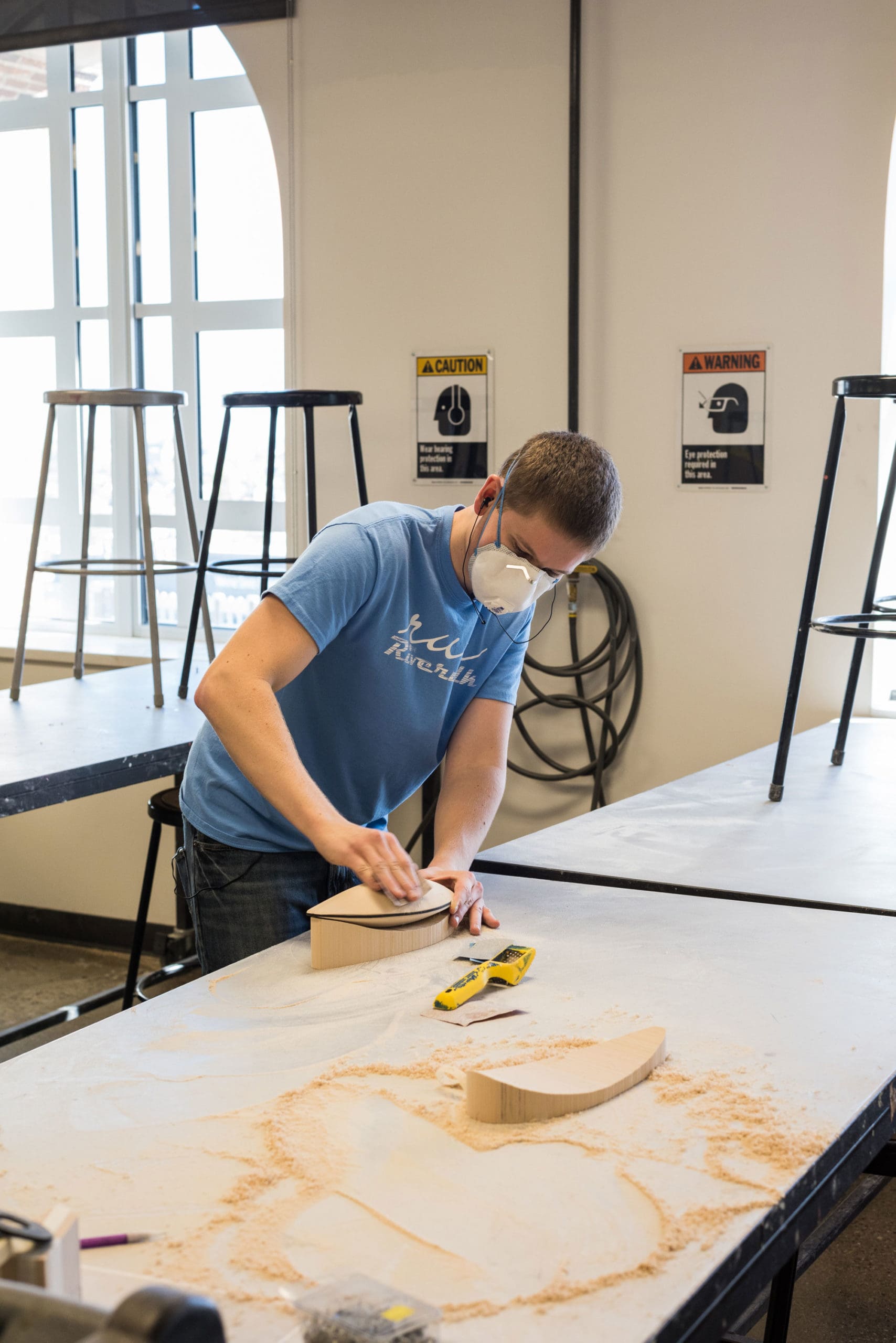 Image of a student sanding a piece of wood in a workshop