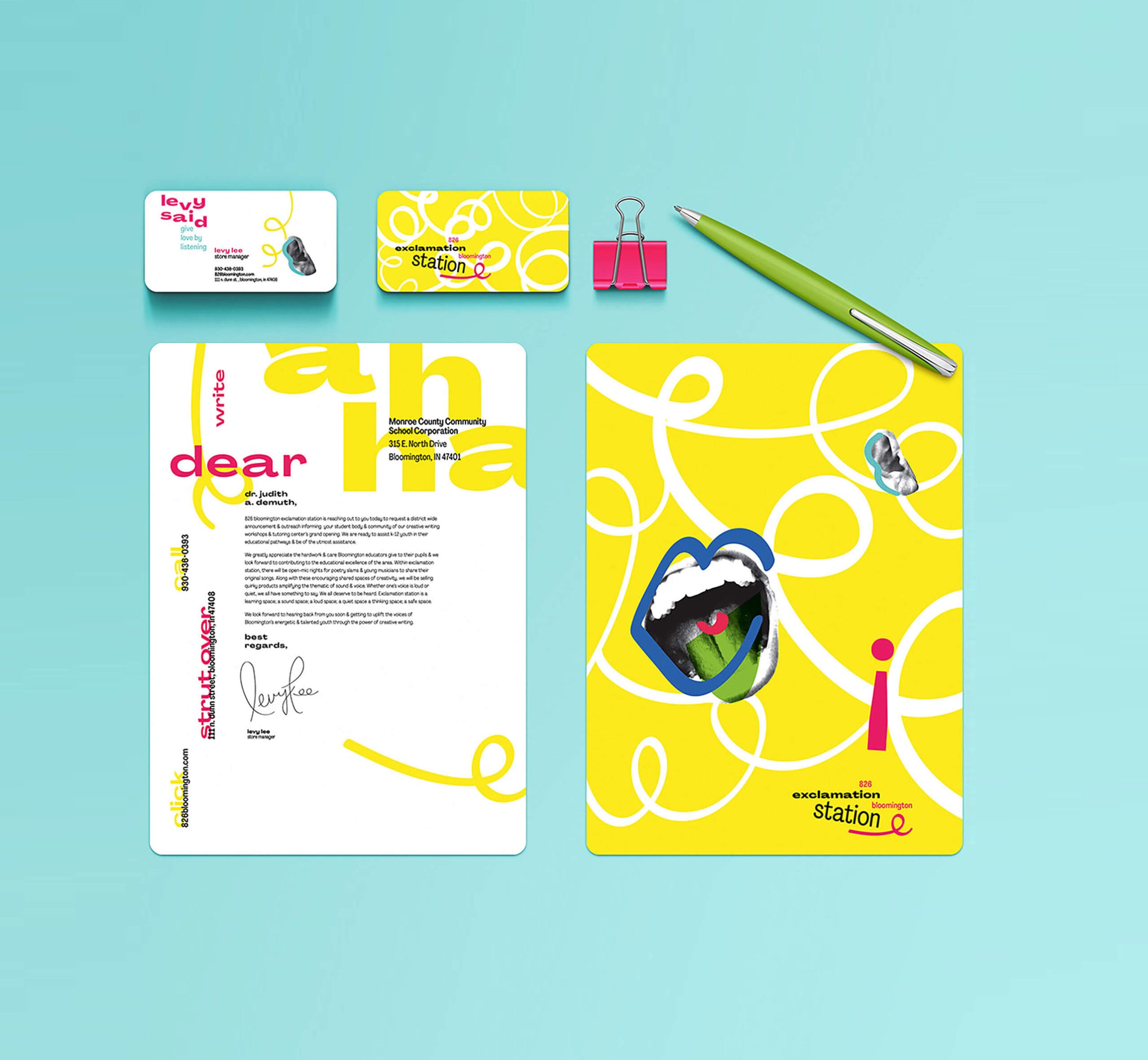 Brand system of the Exclamation System. Shows two posters, two business cards, a pink binder clip, and a green pen against a blue background. The left poster is white with pink and yellow decorative text and small black informational text. The right poster is yellow with white decorative loops and an image of an open mouth with blue lips. The business cards show the same images in a smaller form.