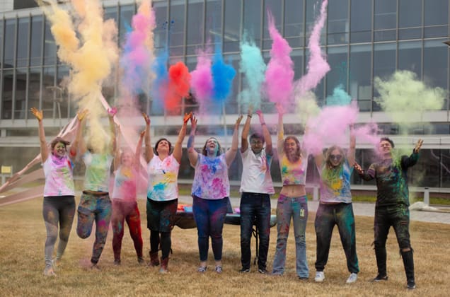 students standing in the sculpture garden throwing chalk colored dust in the air