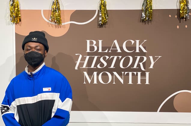 Student standing in front of the Black History Month banner
