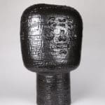 artwork of Ebitenyefa Baralaye.. Black ceramic sculpture comprised of a large cylinder on top of a smaller one.