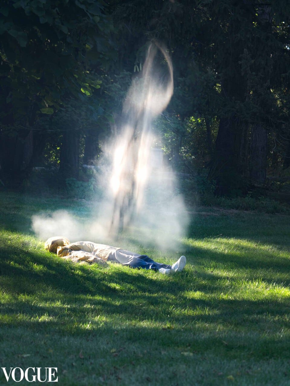 A person laying down in a lush meadow with a waterfall