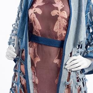 Fiber & Textiles Design. Closeup of a maroon dress with a blue fabric belt and a cream colored floral pattern. On top is a shredded light and dark blue cardigan