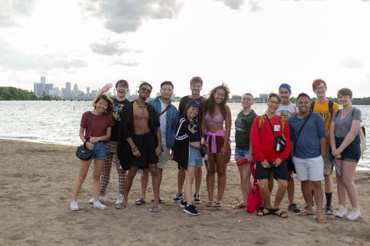 Group of students smiling and posing on a beach on Belle Isle