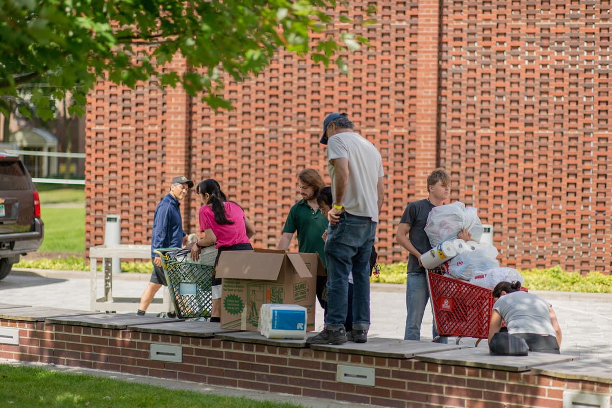 Photo of students and their families outside the Yamasaki Building with dorm supplies on move-in day