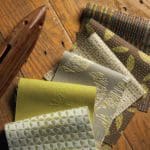 Various green and brown patterned fabric swatches on a hardwood table